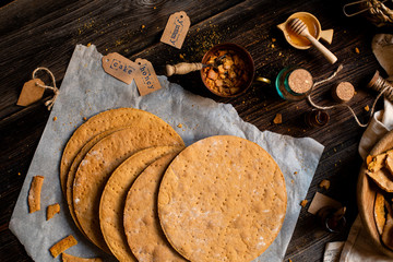 Overhead shot of homemade baked layers of Russian traditional honey cake on baking paper on wooden...