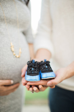 Expecting parents holding little baby boy shoes