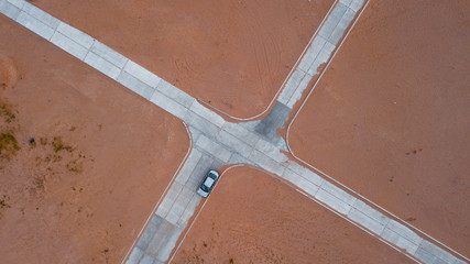 Crossroad and a lonely car in the desert seen from the sky. Aerial view