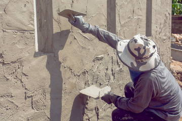 Construction workers plastering building wall using cement plaster
