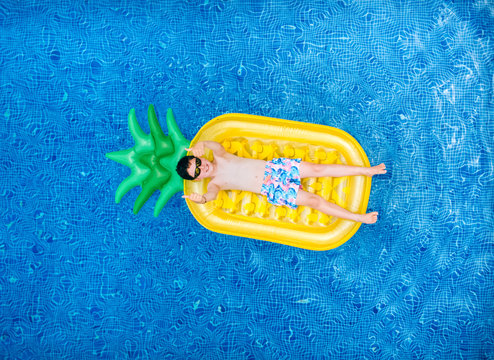 Little boy lying on a pineapple-shaped float in a swimming pool