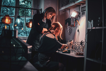 Expirienced master and her new assistant are working together doing new lamp.