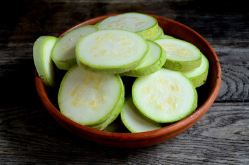 Sliced zucchini in a ceramic bowl on a rustic wooden table.