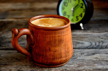 Home coffee with milk in a ceramic cup, in the early morning. Alarm clock.