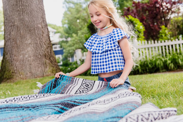 Young girl setting up blanket on grass