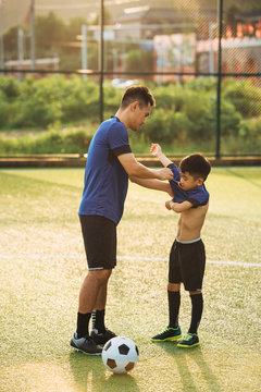 Father helping son dressing up in soccer uniform