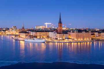 Riddarholmen - part of the historical Old Town (Gamla Stan) in Stockholm, Sweden, at dusk, in winter, surrounded by ice.
