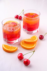 Jelly dessert with strawberries in drink glass with cherry berries and orange slices nearby