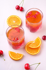 Jelly dessert with strawberries in drink glass with cherry berries and orange slices nearby