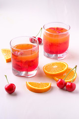 Jelly dessert with strawberries in drink glass with cherry berries and orange slices nearby