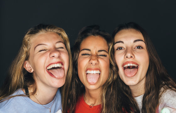 Studio portrait of cute teen girls sticking out tongue.