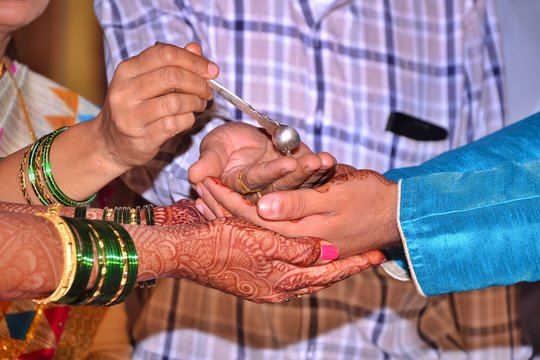 Maharashtrian Wedding Ritual - Kanyadan ritual - An Indian bride and groom holding hands together and Brides parents pouring water with spoon on it