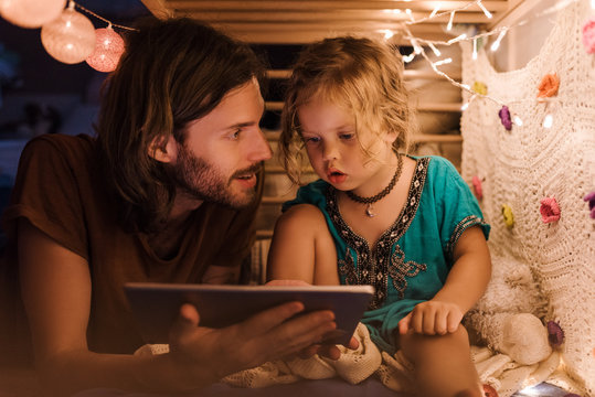 Content father with girl watching tablet