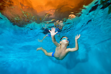 A little boy is floating underwater in the pool with his arms outstretched. Dancing underwater. Creative. Portrait. Underwater photography. Horizontal orientation of the image © alexbard