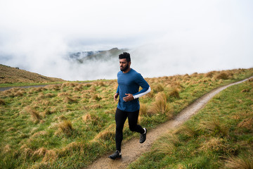 Athletic man jogging along a dirt path in the mountains.