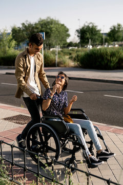Young woman sitting on a wheelchair and her boyfriend walking