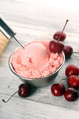 Cherry and vanilla ice cream scoop with fresh cherries and mint on a rustic background