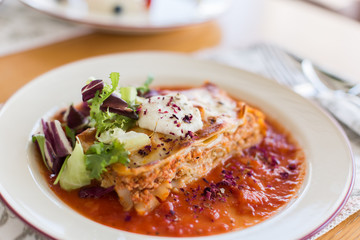 Tasty delicious italian dish lasagna with tomato sauce and cream cheese with green salat. Food, tasty dinner concept