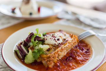 Tasty delicious italian dish lasagna with tomato sauce and cream cheese with green salat. Food, tasty dinner concept