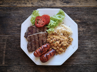 Brazilian food dish - Barbecue with beans, rice and salad.