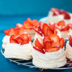 Beautiful pavlova cakes with strawberries on a blue background. Selective focus. Tasty sweet breackfast. Wedding morning. Meringue with cream.