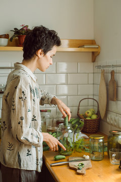 The girl puts the cucumbers in a jar for pickling