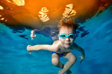 Sports boy swimming underwater in the pool. Posing for the camera in swimming goggles. Bottom view from the bottom of the pool. Portrait. Underwater photography. Horizontal view © alexbard