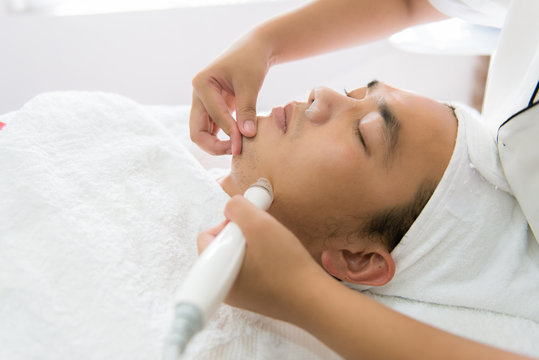 Man receiving facial treatment in spa - Powered by Adobe