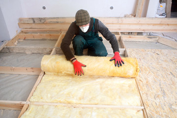 Caucasian Construction Worker with Roll of Insulating Material, Floor Insulating by Mineral Wool.