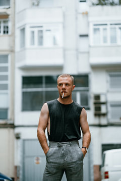 Stylish man smoking surrounded by buildings