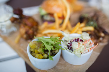 Food plate with fried chicken wings, burger, fried potatoes, sauce, salad, grilled meat . Fast unhealthy tasty food concept