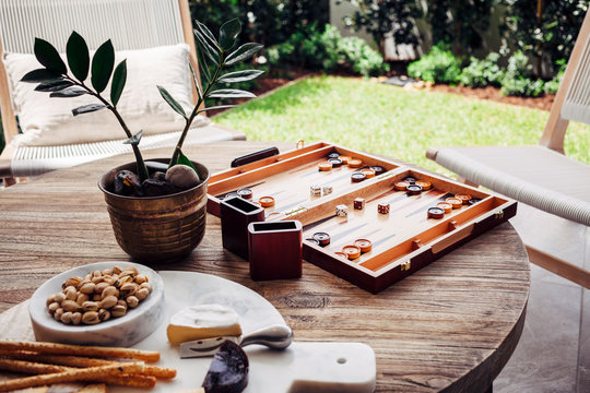 Wooden table with cheese platter and board game in backyard of new home