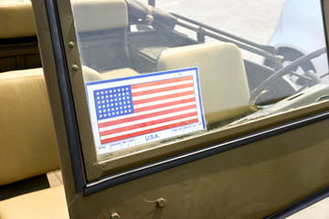 Vehicle inspection decal with Americain flag with 48 stars on windshield of olive green WWII open military vehicle. This decal was used in the Operation Overlord landings on June 6, 1944.