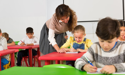 Teacher helping children during lesson