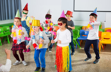 School kids with teacher in festive hats having fun