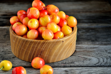 Sweet cherry in a wooden bowl on a wooden table.