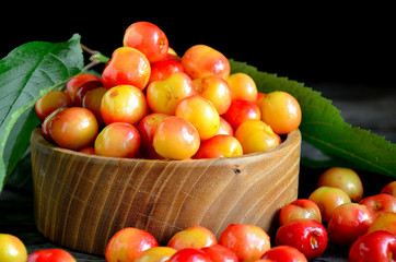 Sweet cherry in a wooden bowl on a wooden table.