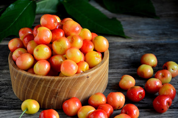 Sweet cherry in a wooden bowl on a wooden table.