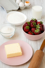 Strawberry pie ingredients (flour, eggs, butter, milk, sugar, strawberry), side view. Cooking strawberry pie or cake. Close-up.