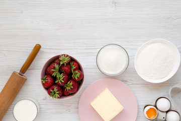 Strawberry pie ingredients (flour, eggs, butter, milk, sugar, strawberry), overhead view. Cooking strawberry pie or cake. Flat lay, top view, from above. Space for text.