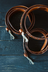 three leather brown belts on dark wooden background