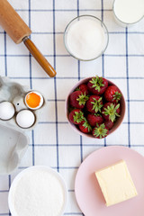 Strawberry pie ingredients (flour, eggs, butter, milk, sugar, strawberry), view from above. Cooking strawberry pie or cake. Flat lay, top view, overhead.