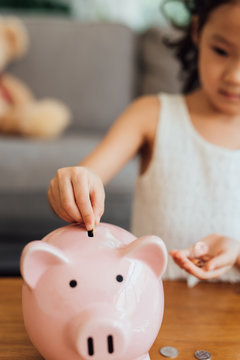 Chinese girl putting coins into piggy bank