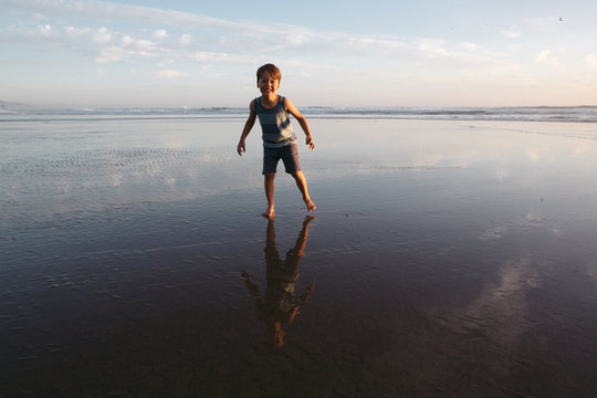 Young boy enjoying freedom on the beach at sunset.