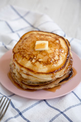 Homemade pancakes with butter and maple syrup on a pink plate, low angle view. Close-up.