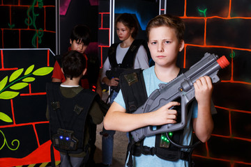 Fototapeta na wymiar teen boy standing with laser pistol in dark lasertag room