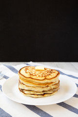 Homemade pancakes with butter on a white plate, low angle view. Closeup.