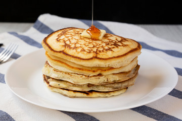 Homemade pancakes with butter and maple syrup on a pink plate, side view. Closeup.