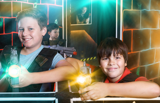 Two happy teen boys standing with laser guns