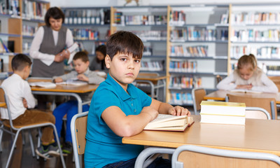 Fototapeta na wymiar Tween boy reading textbooks in school library
